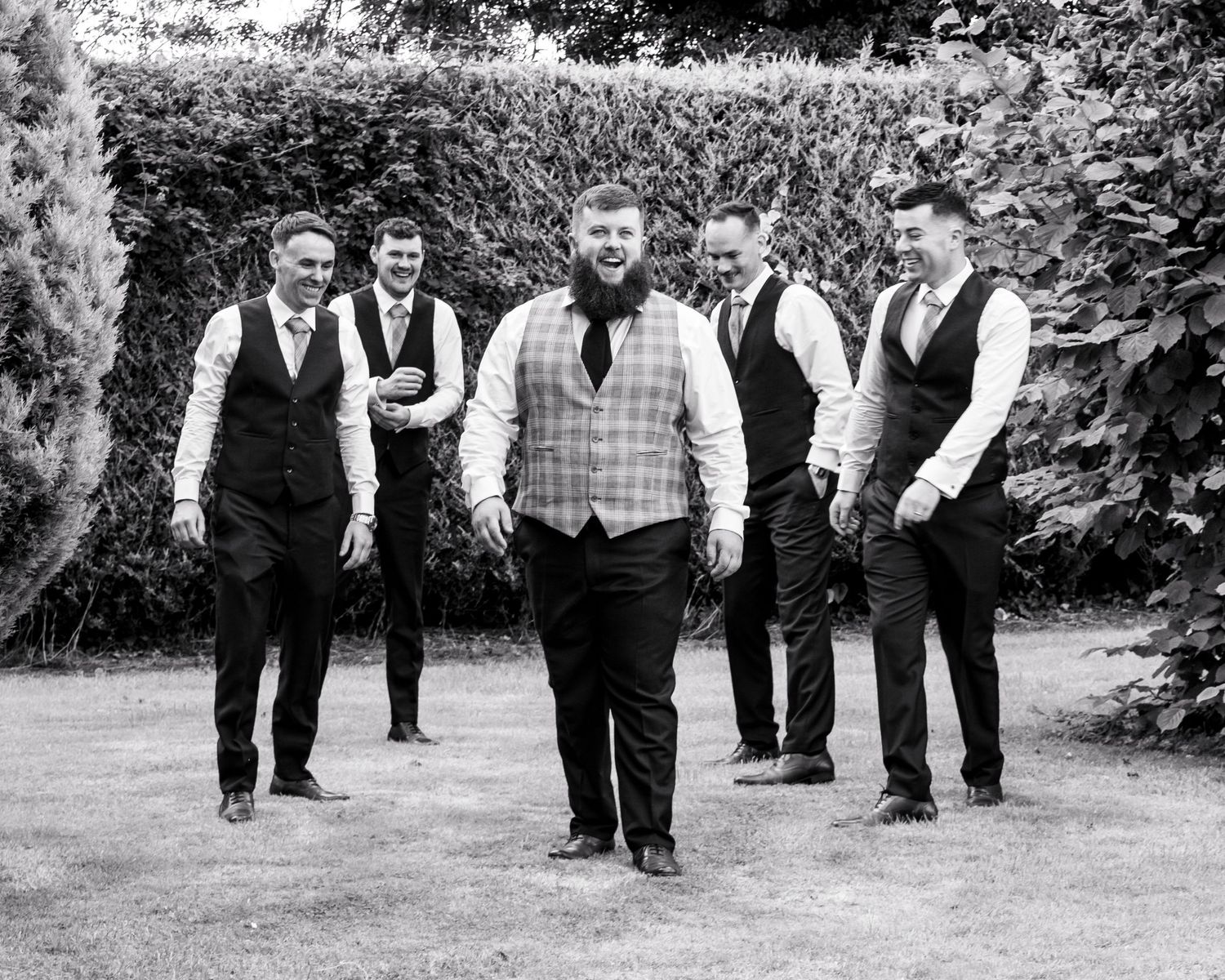 Wedding party members walking together outdoors in matching formal attire.