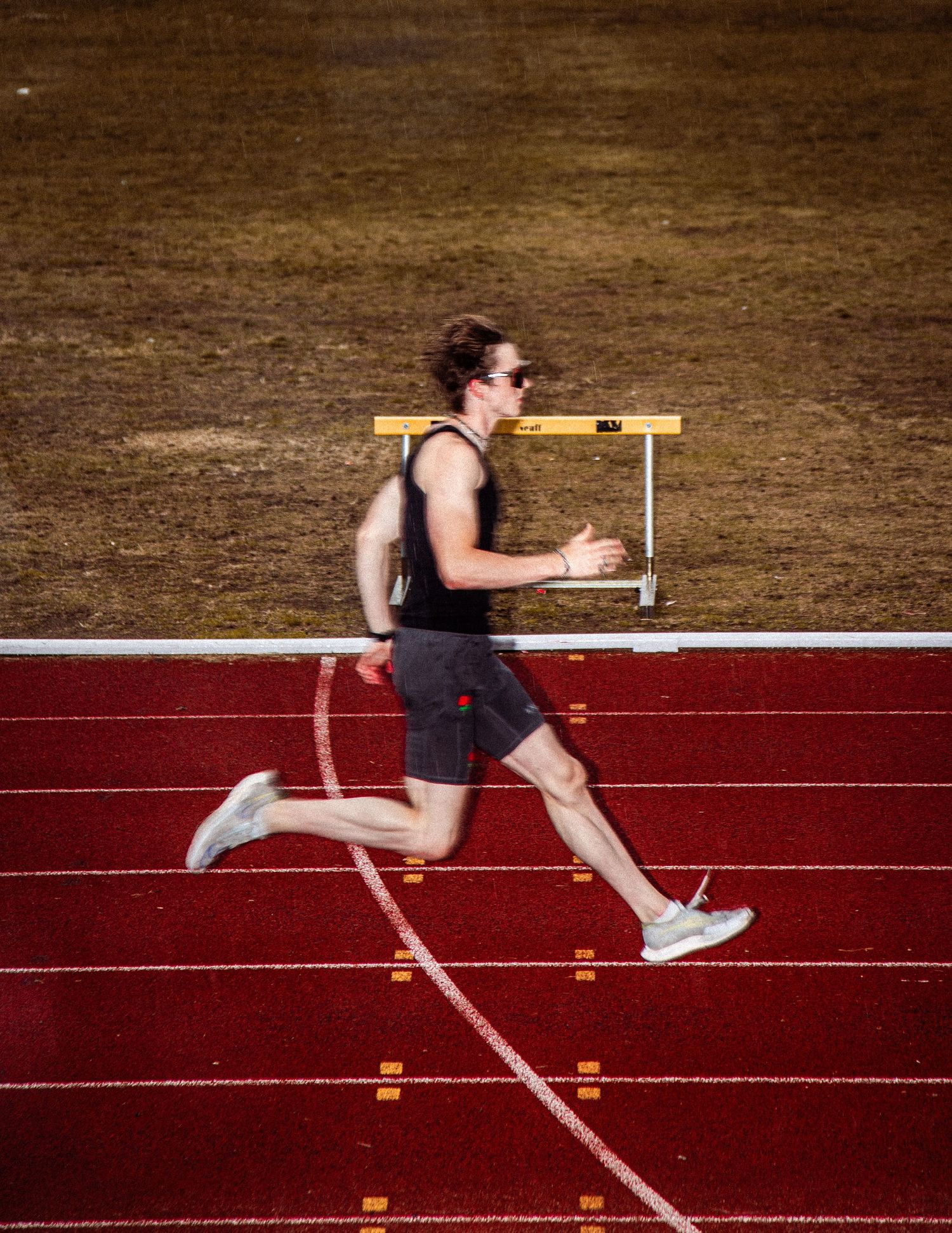 Runner practicing starting blocks technique on a red running track.