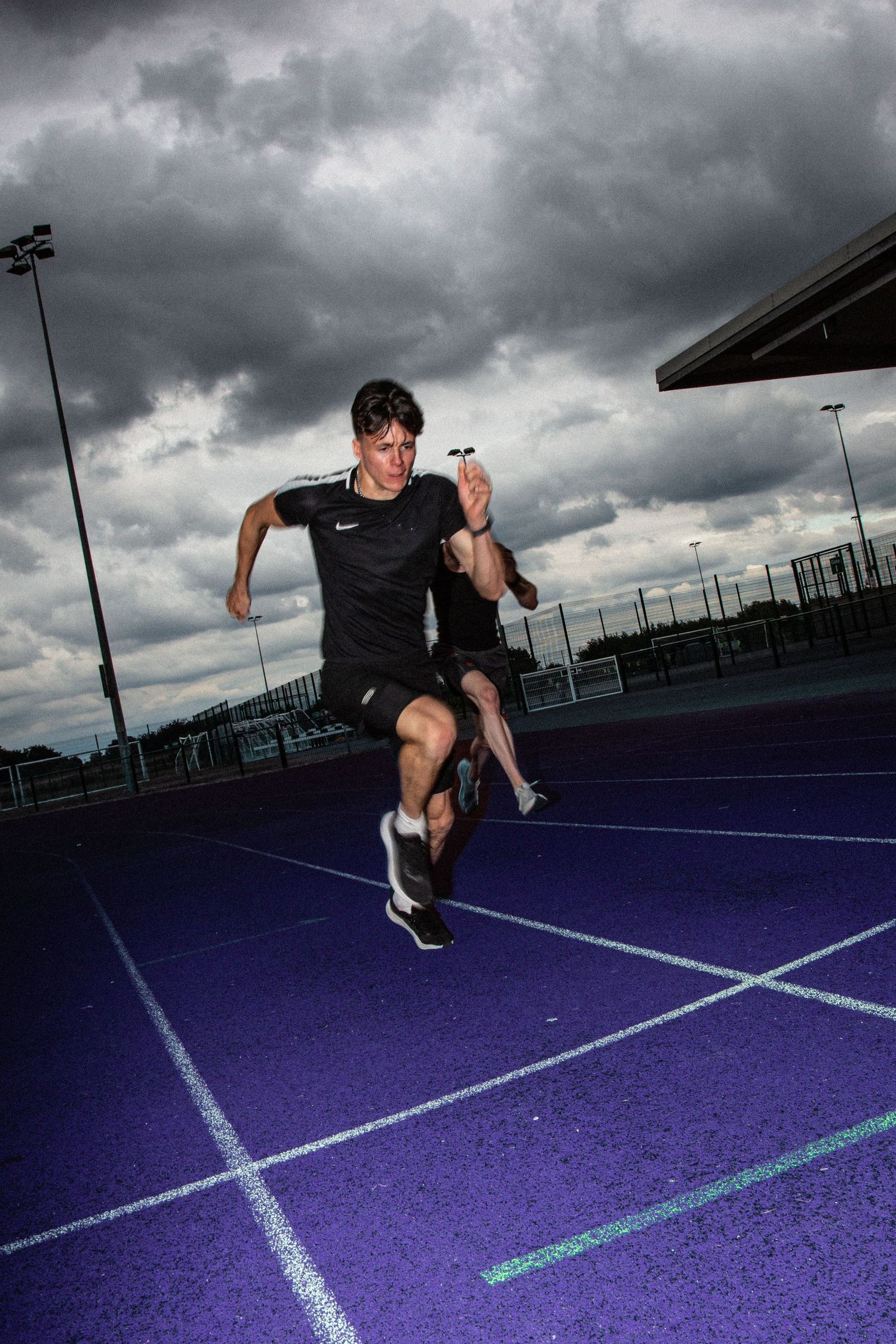 Athletic figure performs dynamic jumping sequence across purple sport court under dramatic stormy sky.
