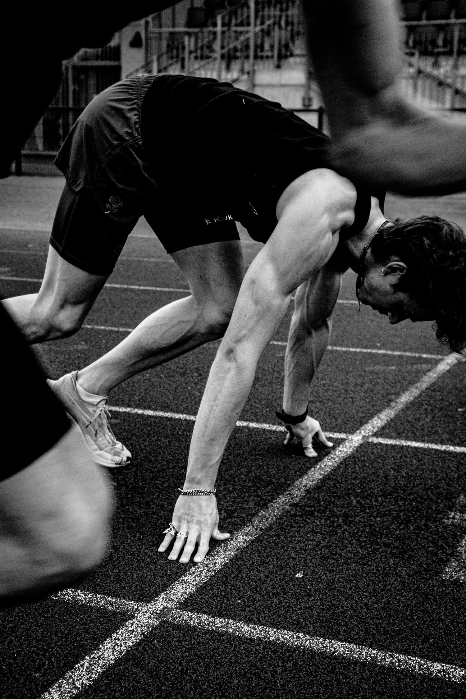 Athlete in starting position on track preparing for sprint.