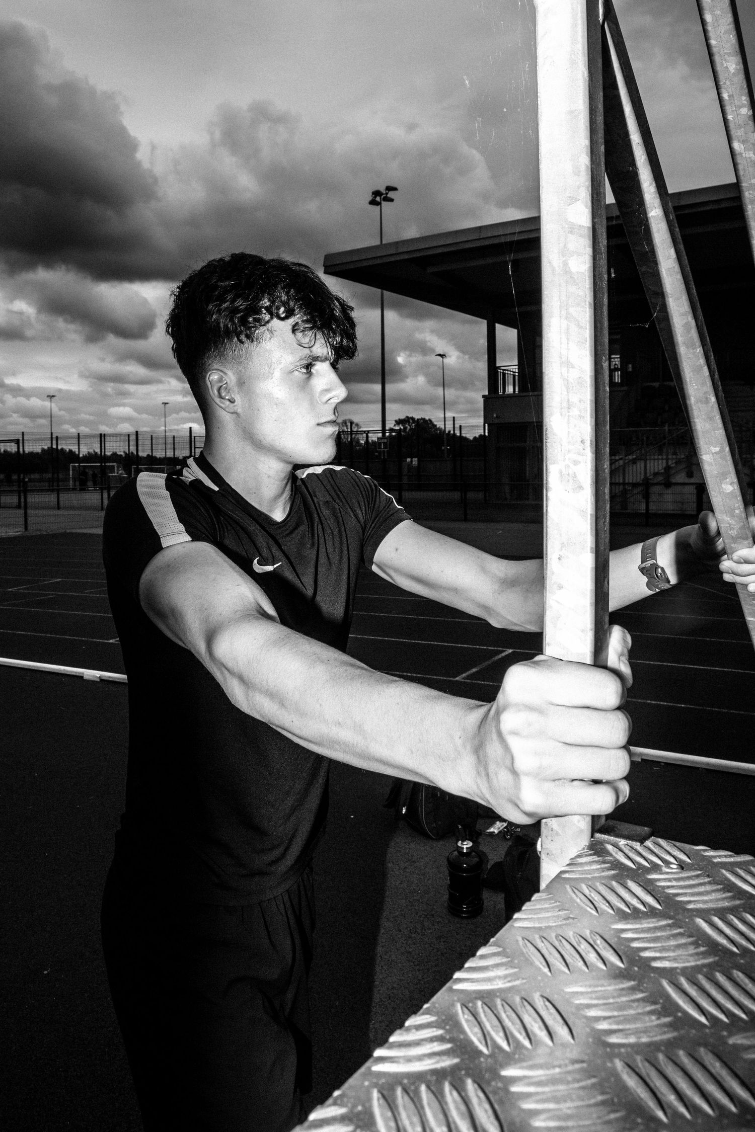 Person gripping metal bars during outdoor workout with cloudy sky backdrop.