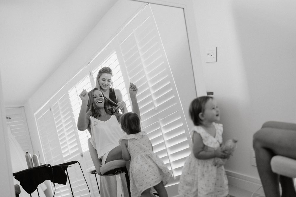 Black and white candid photo of people relaxing in a bright room with white plantation shutters in the background.