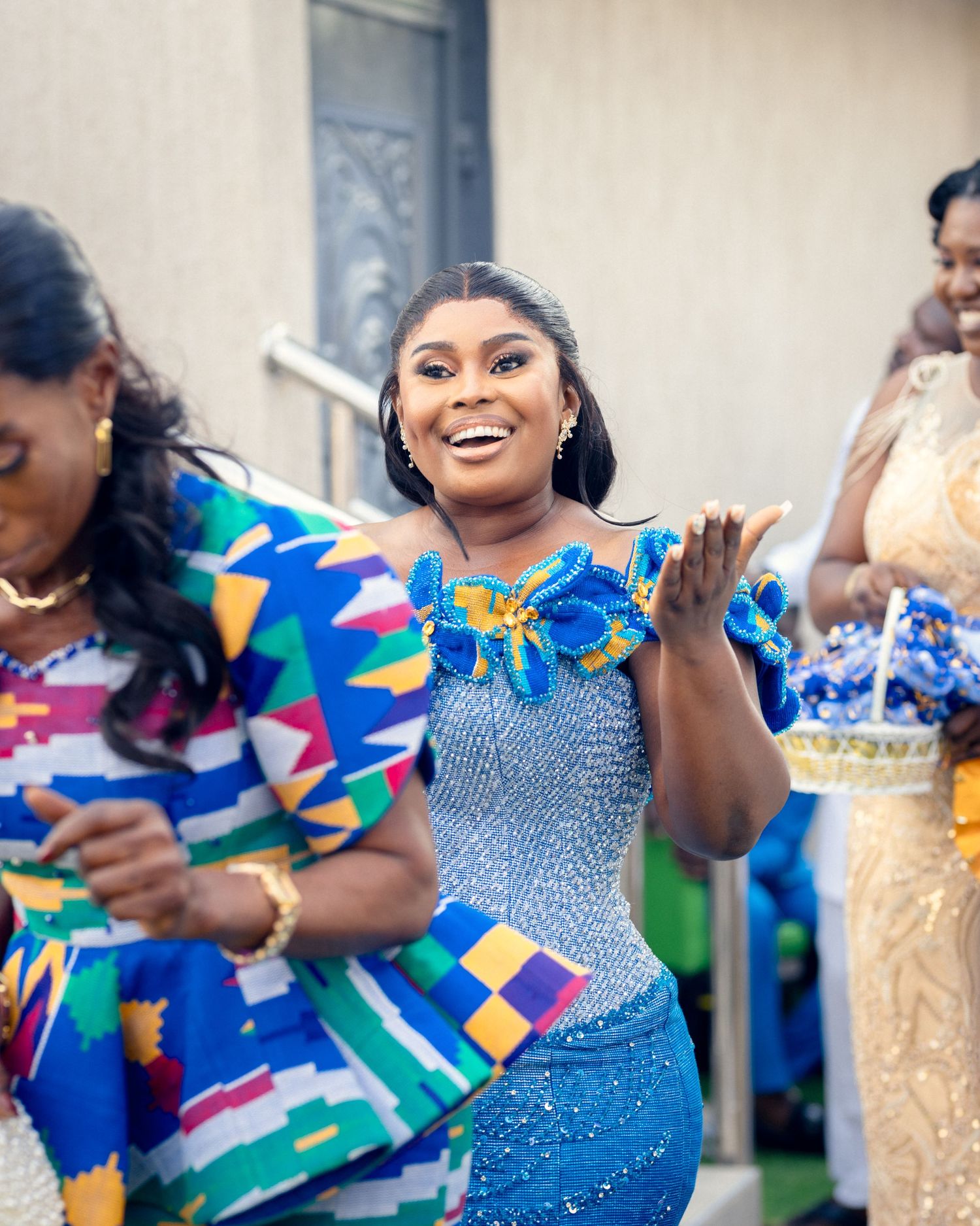 Joyful celebration at a wedding with guests wearing vibrant blue and multicolored African print dresses.