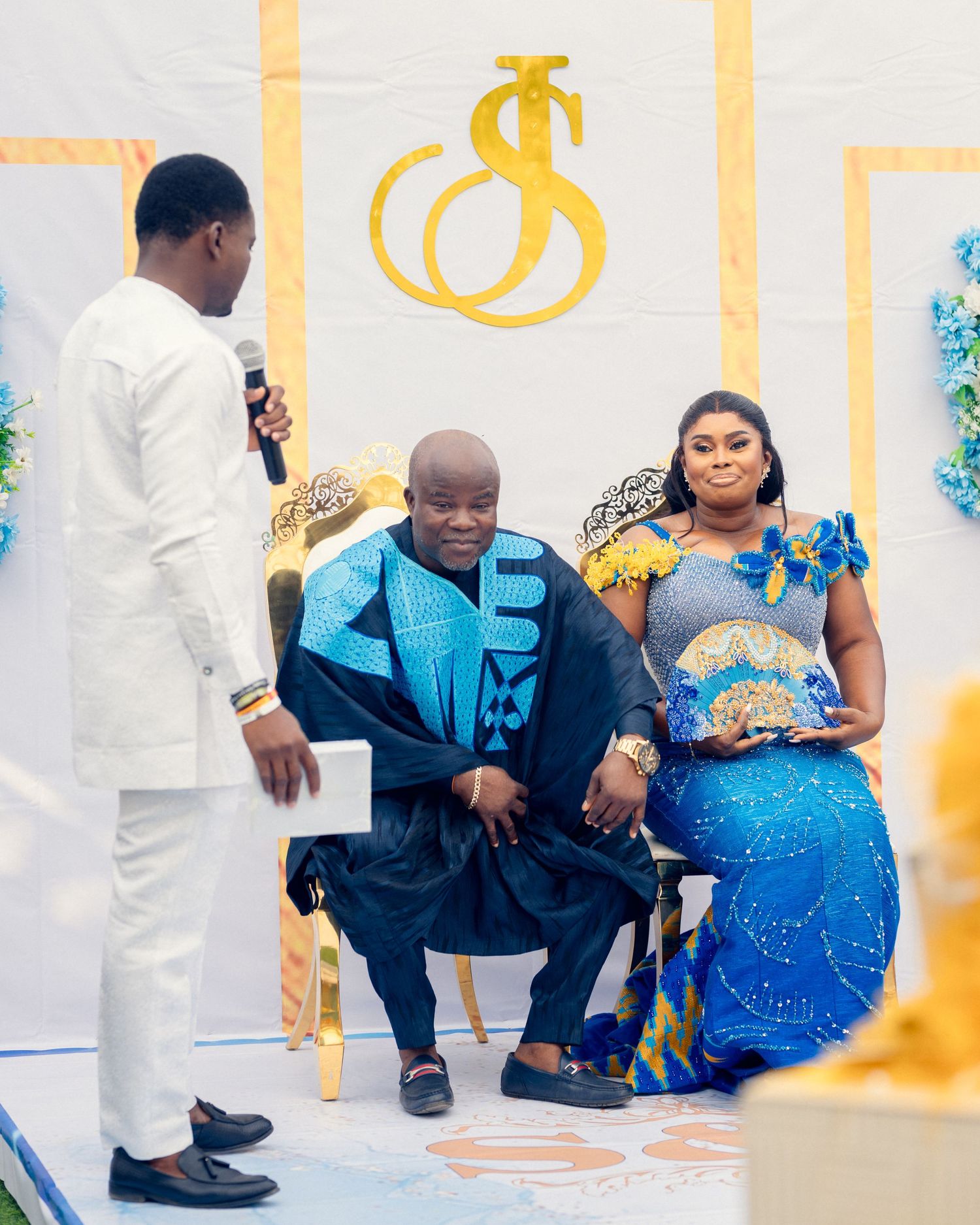 Wedding ceremony setup with blue and white decor featuring a golden monogram on the wall.