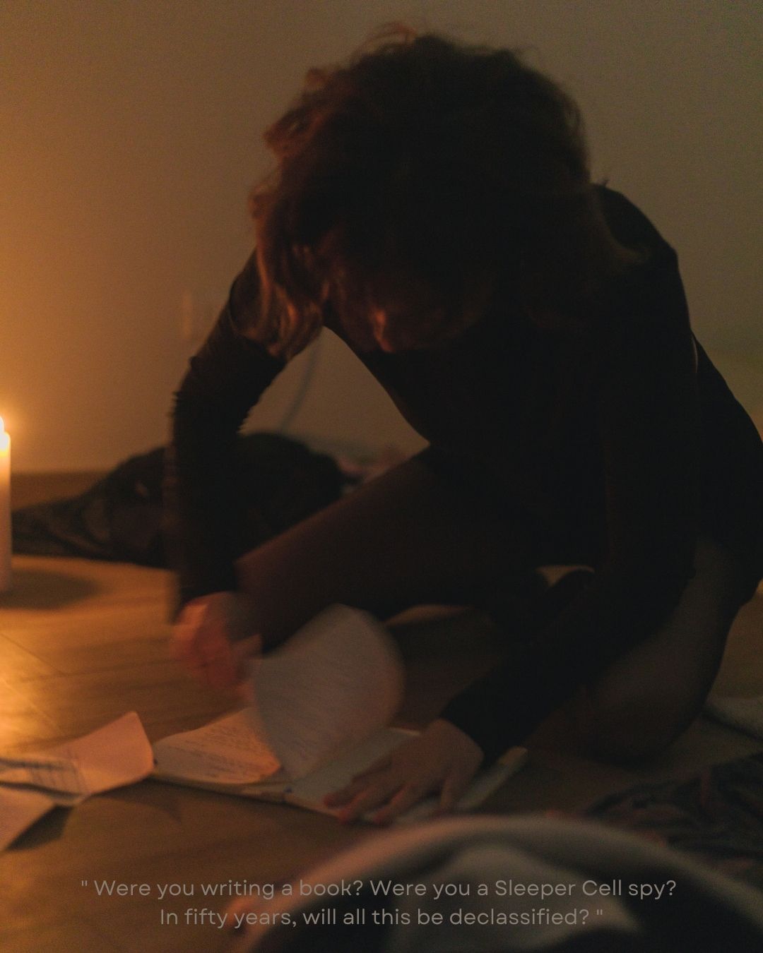 A person reading papers by candlelight on a floor with a mysterious quote overlay in dim lighting.