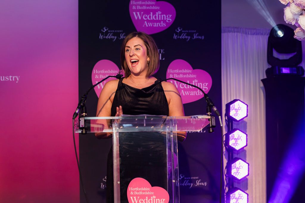 A presenter speaks to an audience in a room decorated with a large star light fixture.