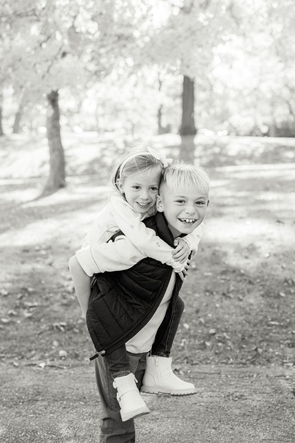 Black and white portrait of two playful children embracing outdoors.