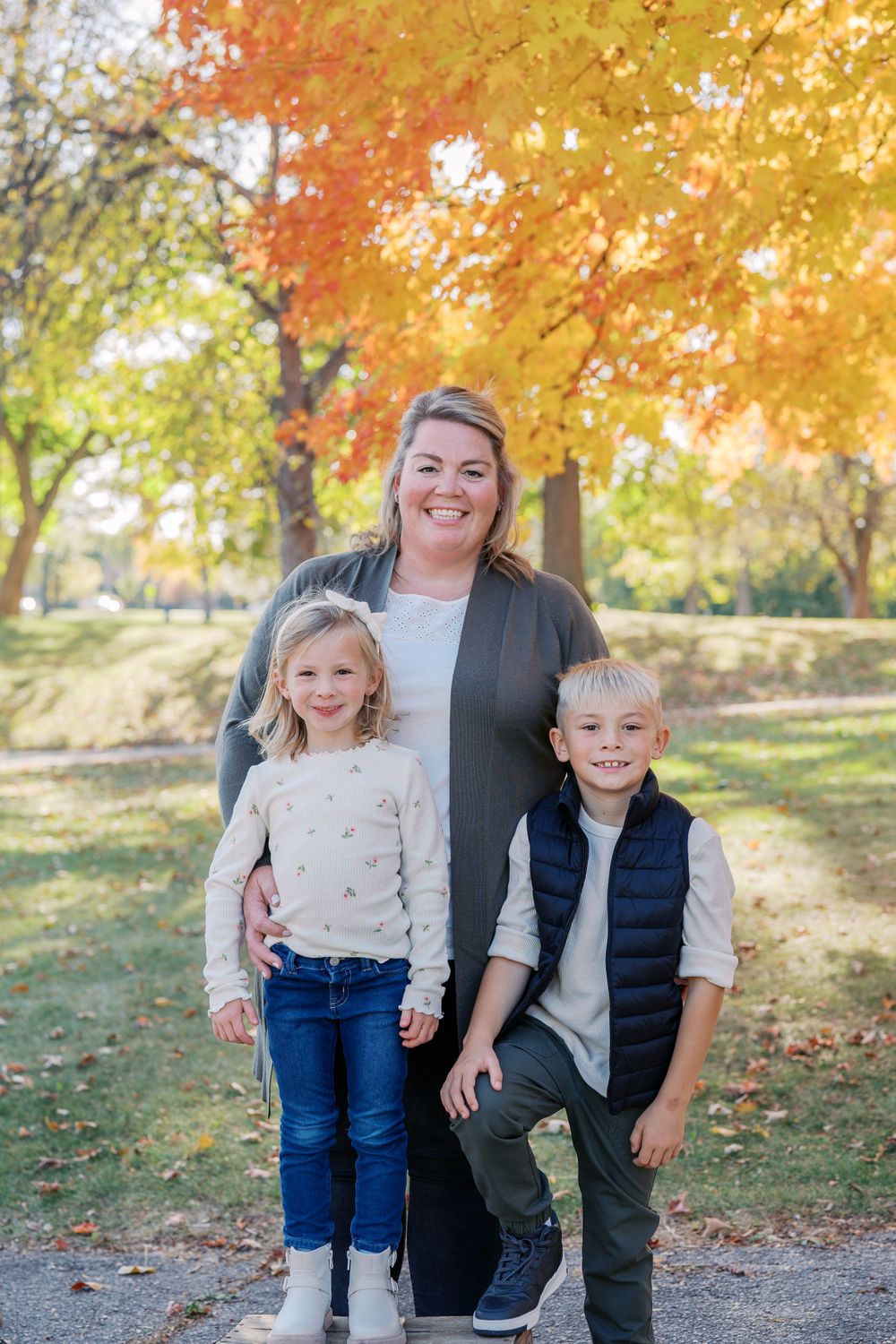 Family photo session in a park with beautiful autumn foliage and golden light.