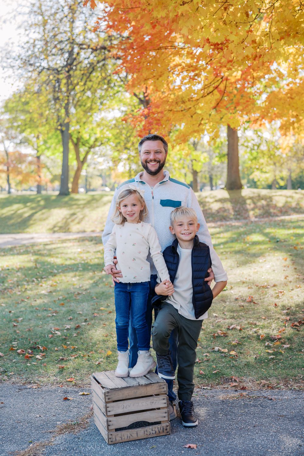 Family portrait session on a path with rustic wooden crates and vibrant fall colors.