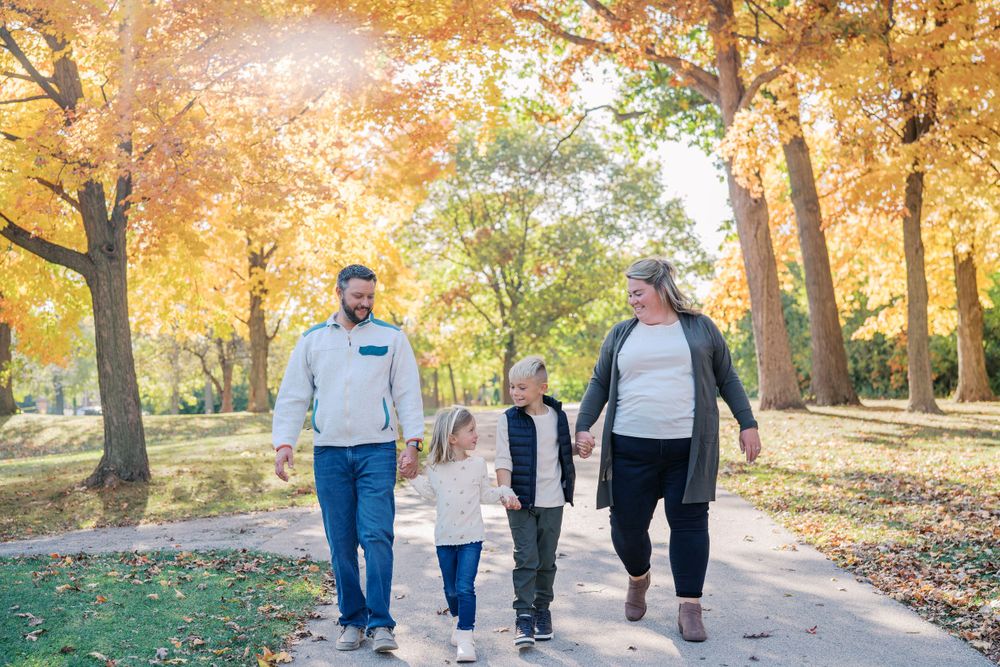 Family walking together on a scenic autumn path surrounded by golden trees.