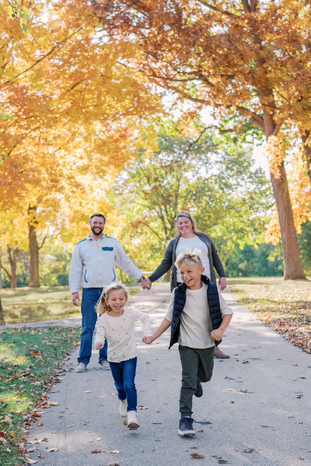 Family enjoying an autumn walk together on a tree-lined path with golden fall foliage overhead.
