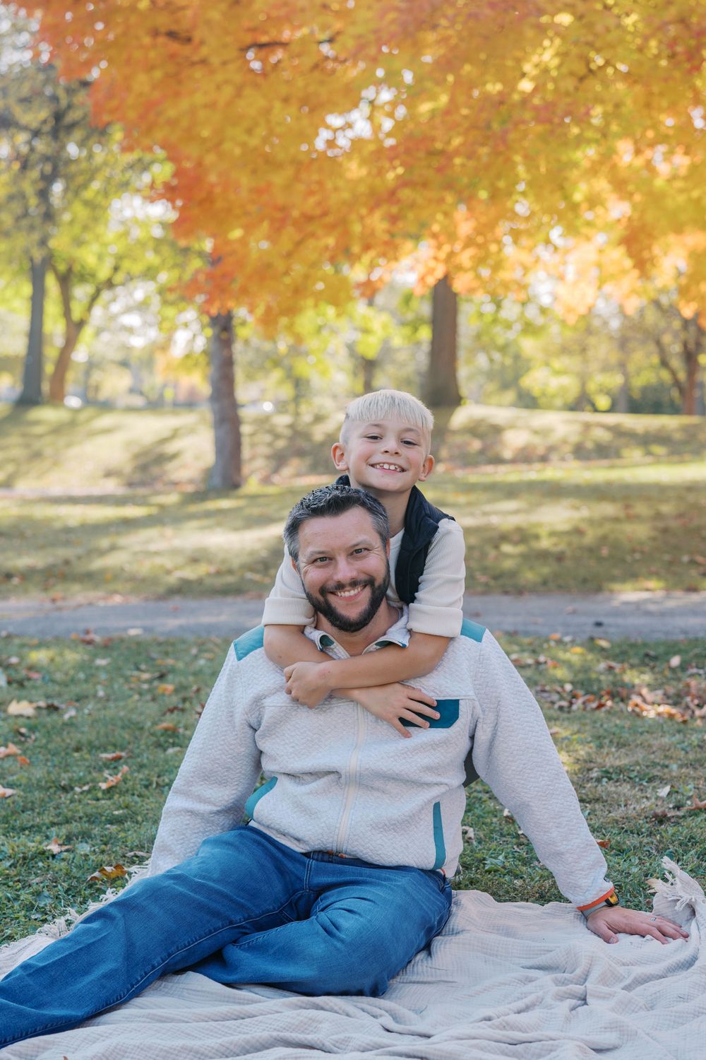 Playful moment captured on a blanket under golden autumn trees.