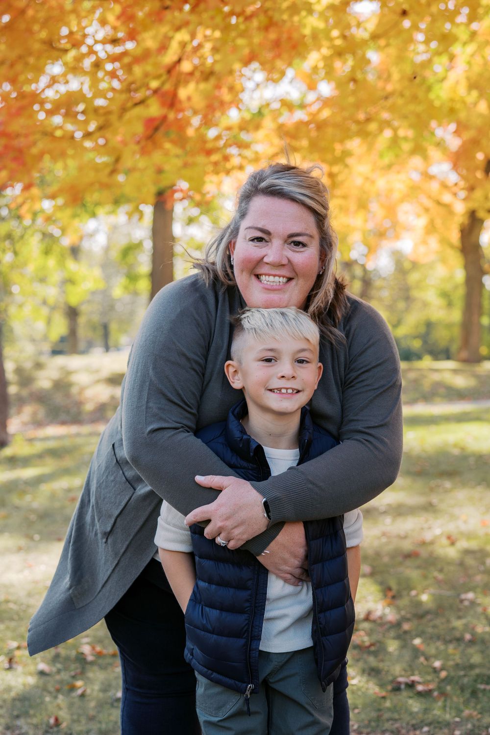 Warm embrace captured during autumn photoshoot with golden leaves in background.