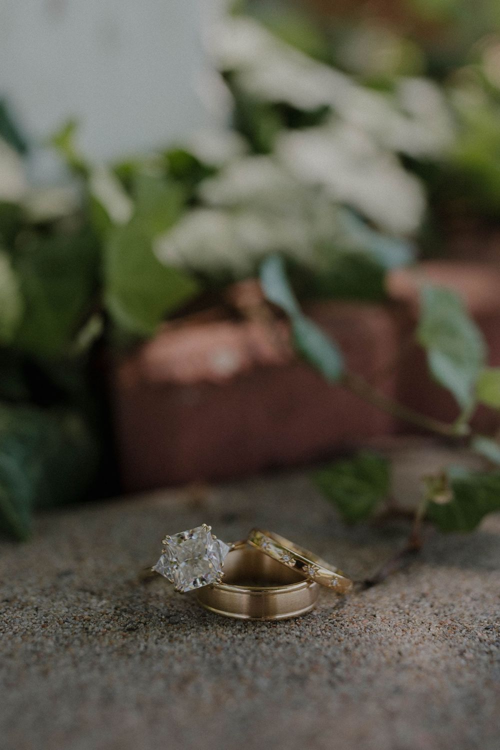 Close-up macro shot of gold wedding rings with diamond detail resting on a textured surface.