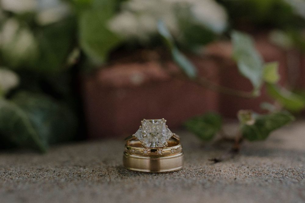 Gold wedding rings nestled in a rustic wooden box with delicate floral details.