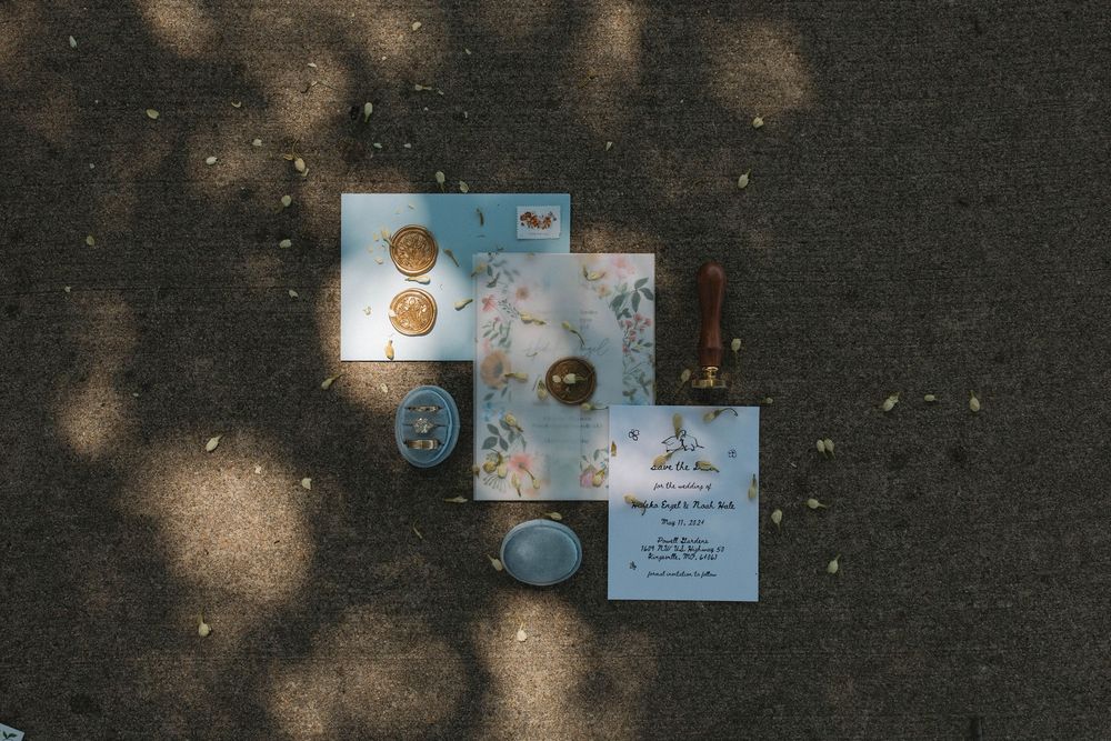 Wedding invitation cards and envelopes scattered on dark textured surface with dappled lighting.