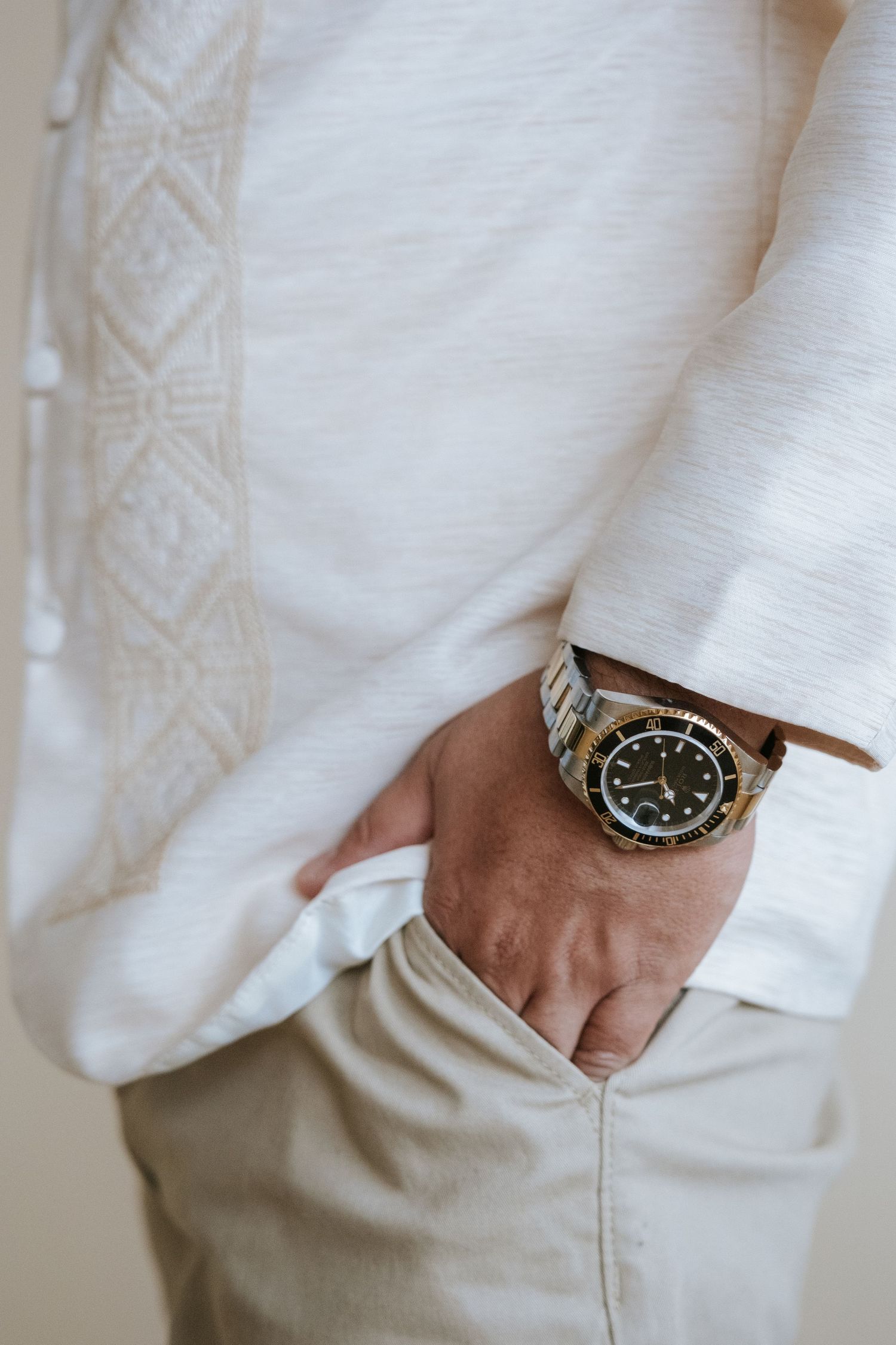 Close-up of a person wearing a white embroidered shirt with a stylish watch on their wrist.