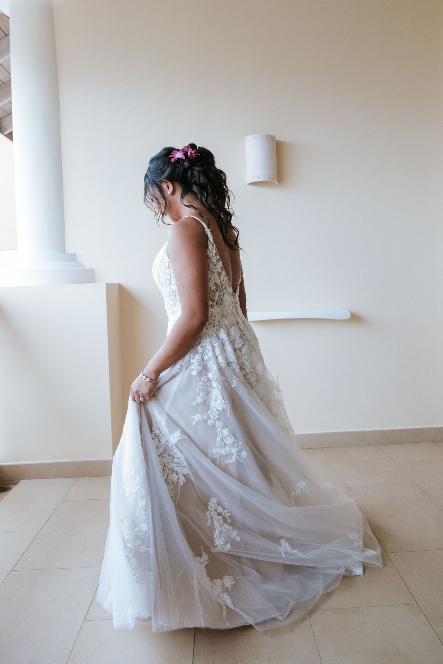 Wedding dress with intricate lace details shown from side view in natural light.