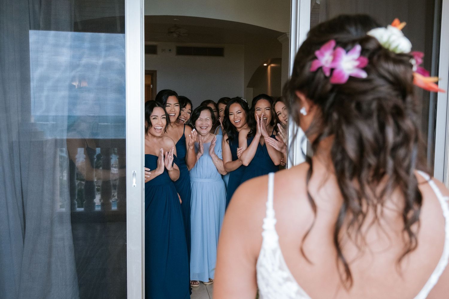 Bridesmaids in blue dresses sharing emotional first look moment.