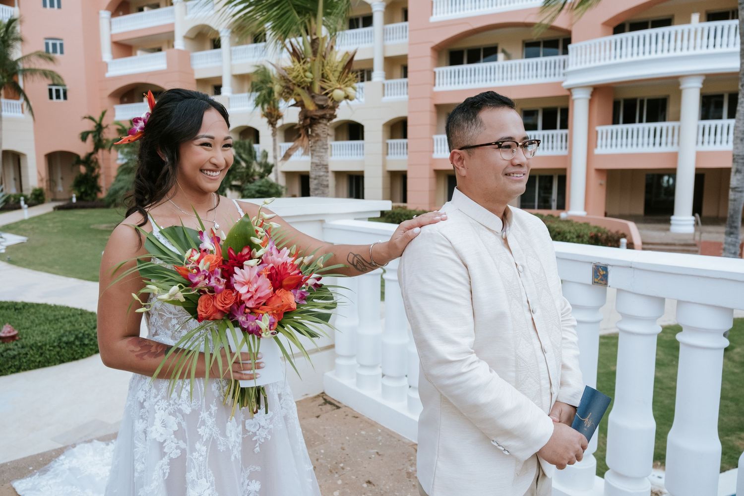 A couple sharing a moment together at a tropical resort with pink architecture.