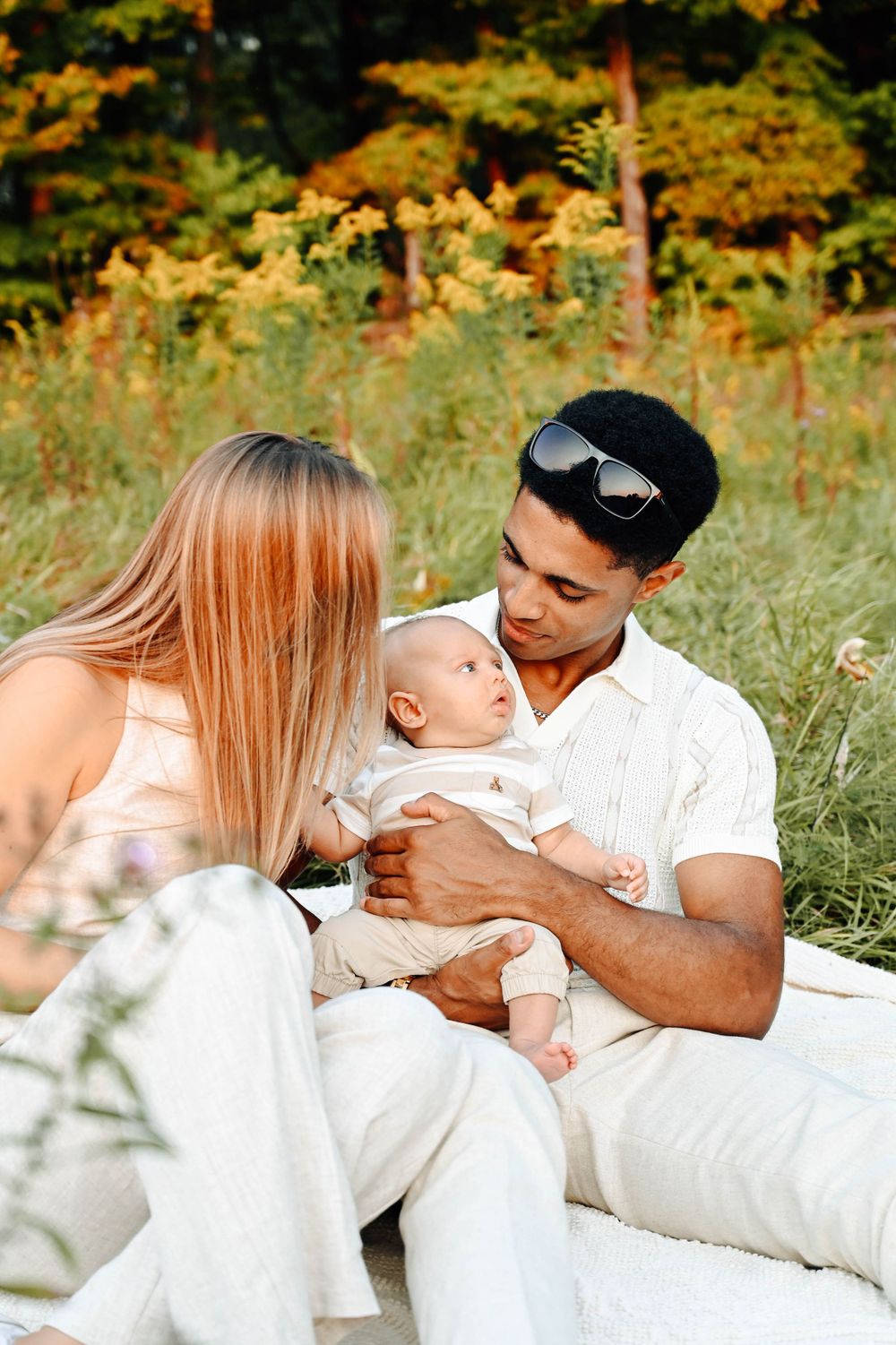 A tender family moment outdoors with a baby as fall foliage creates a warm golden backdrop in nature.