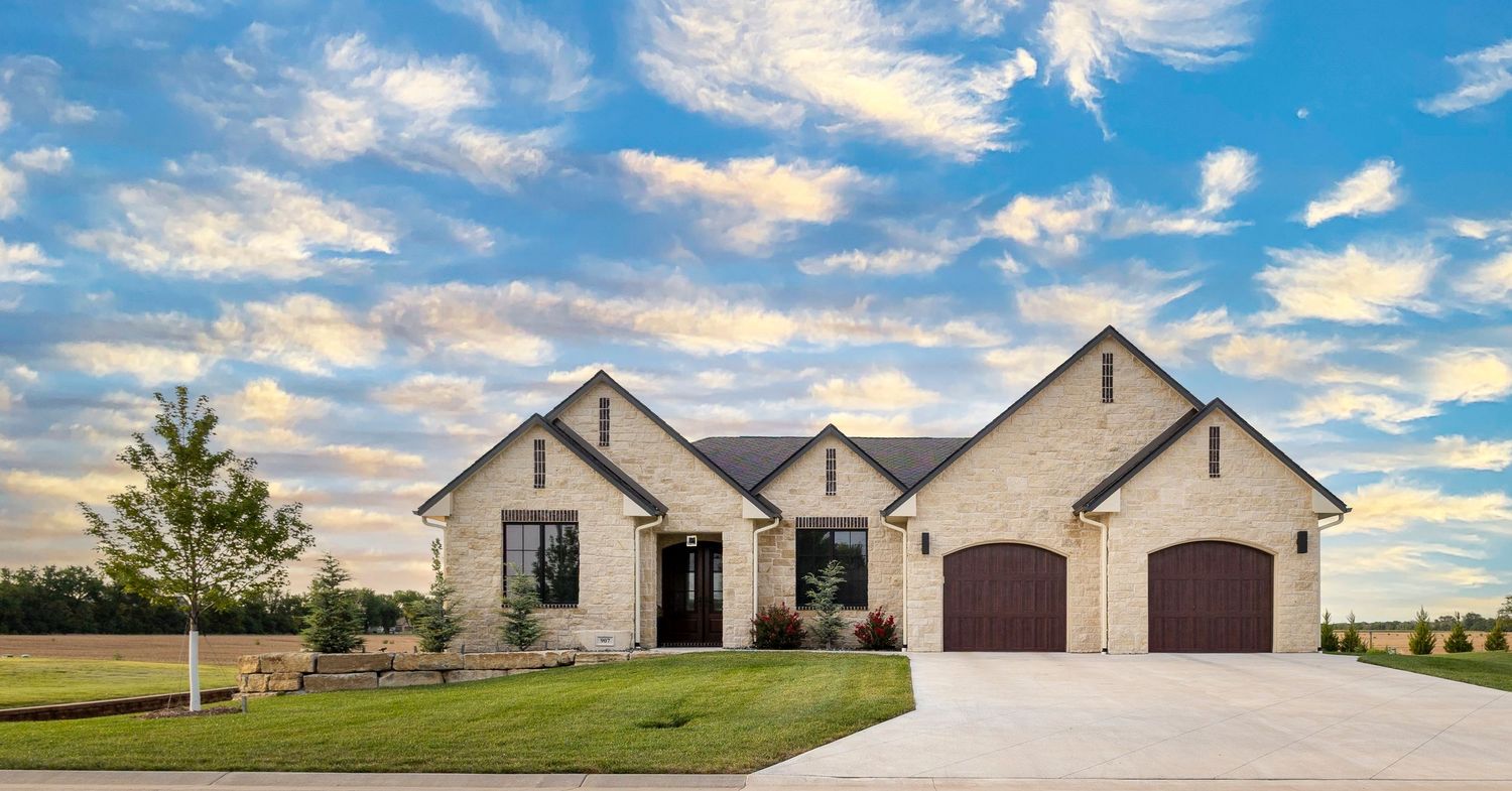 A modern farmhouse style home exterior with white siding and dark accents sits under a dramatic cloudy blue sky.