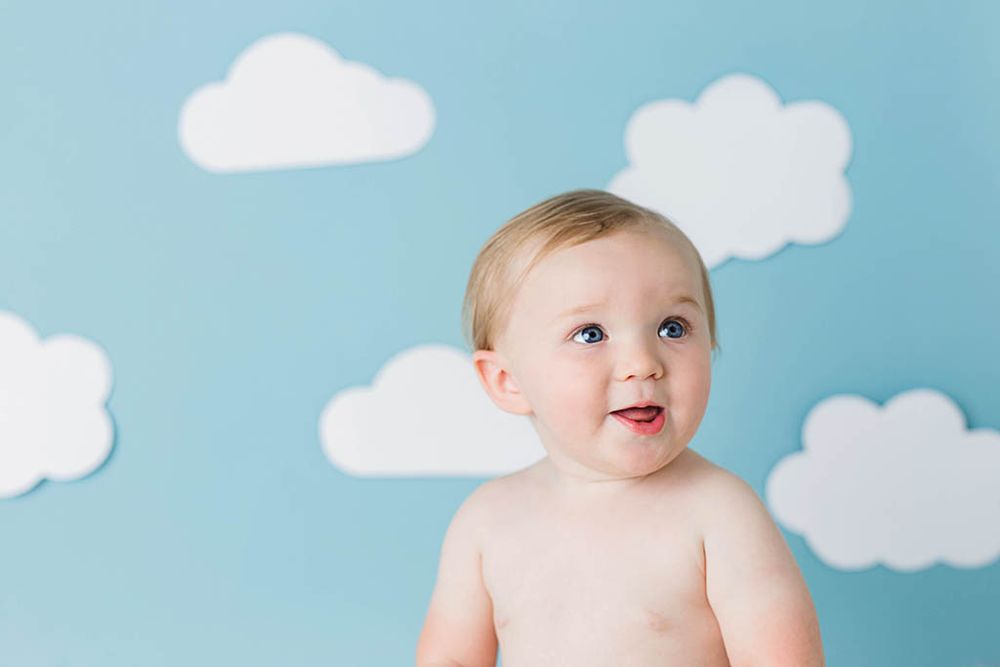 Wildomar baby photographer portrait of adorable baby sitting in front of blue backdrop.