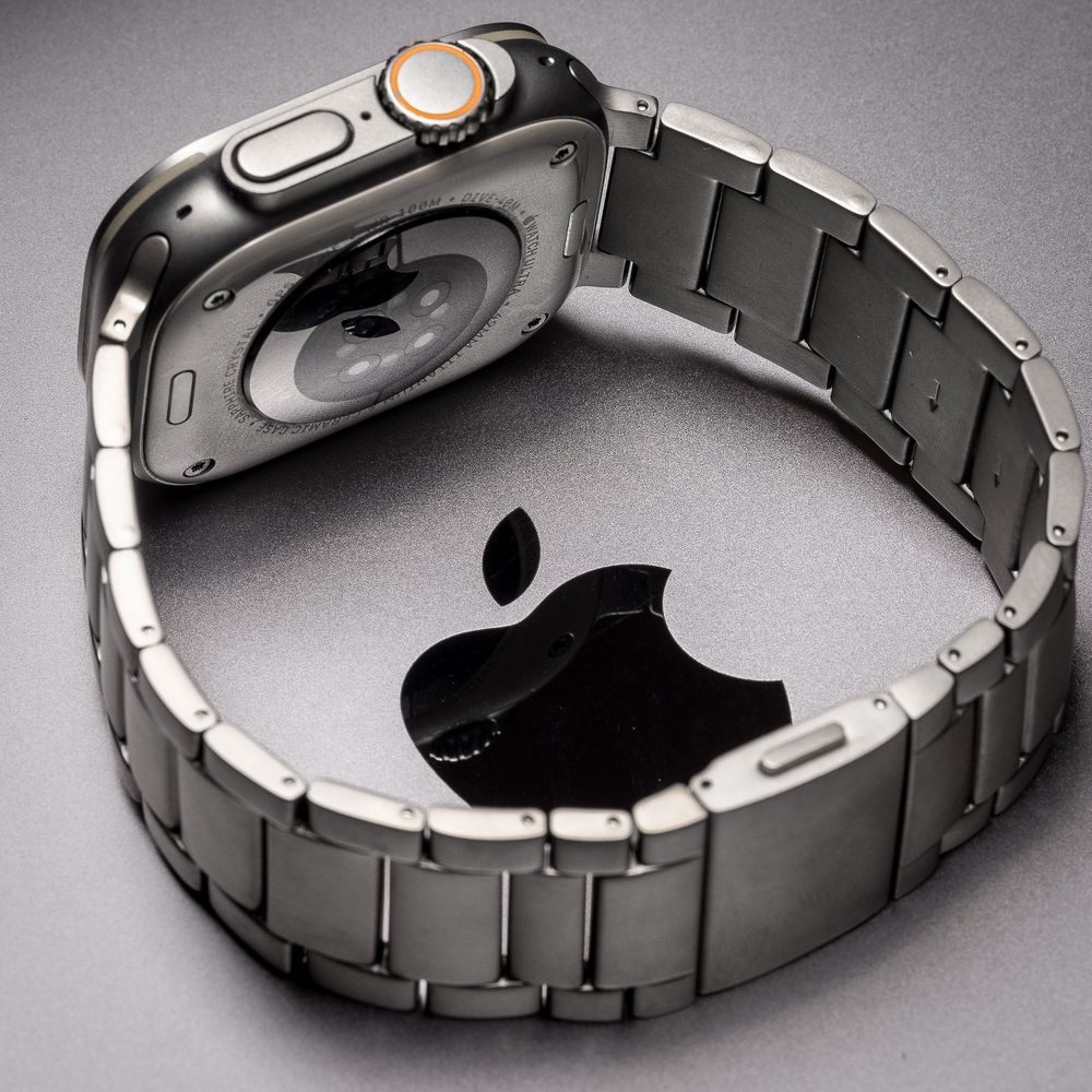 Apple Watch Ultra with titanium link bracelet resting on a surface with Apple logo, showcasing premium smartwatch design.