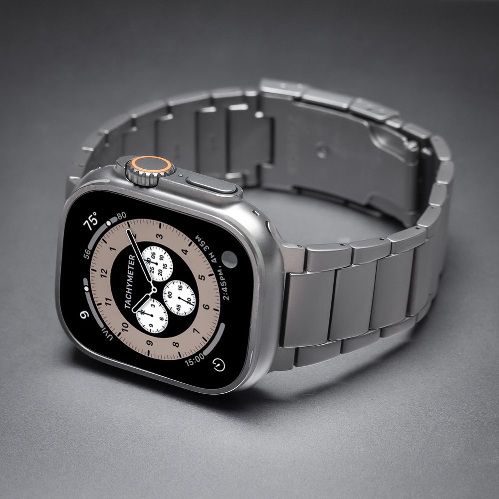 Apple Watch Ultra with titanium case and titanium link bracelet band displayed on gray background.