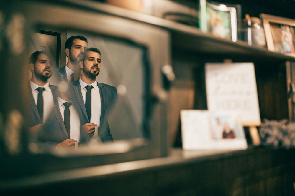 Well-dressed man reflected multiple times in antique mirrors on a wooden shelf.