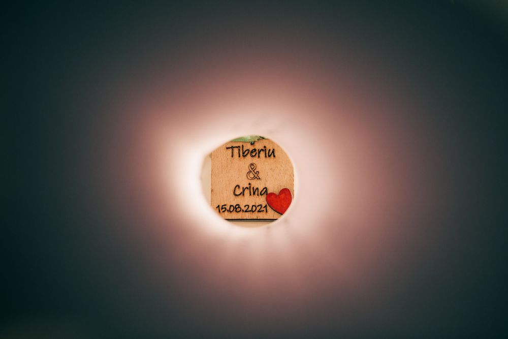 Rustic wooden wedding tag engraved with names Tiberiu and Crina dated 15.06.2021 with red heart detail.