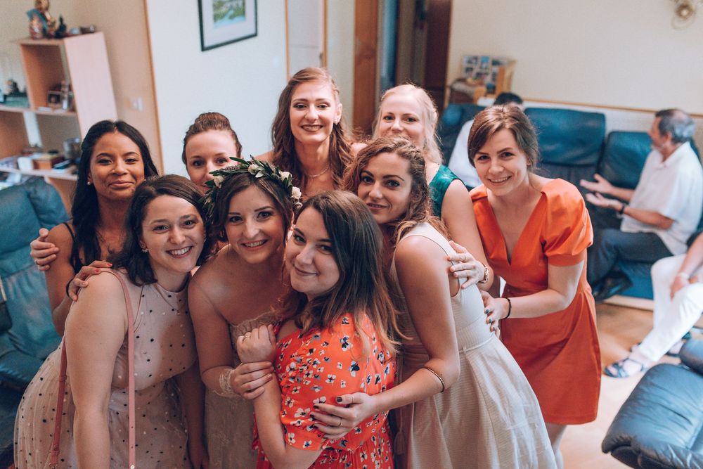 Smiling bride and bridesmaids pose together for group photo during wedding preparations.