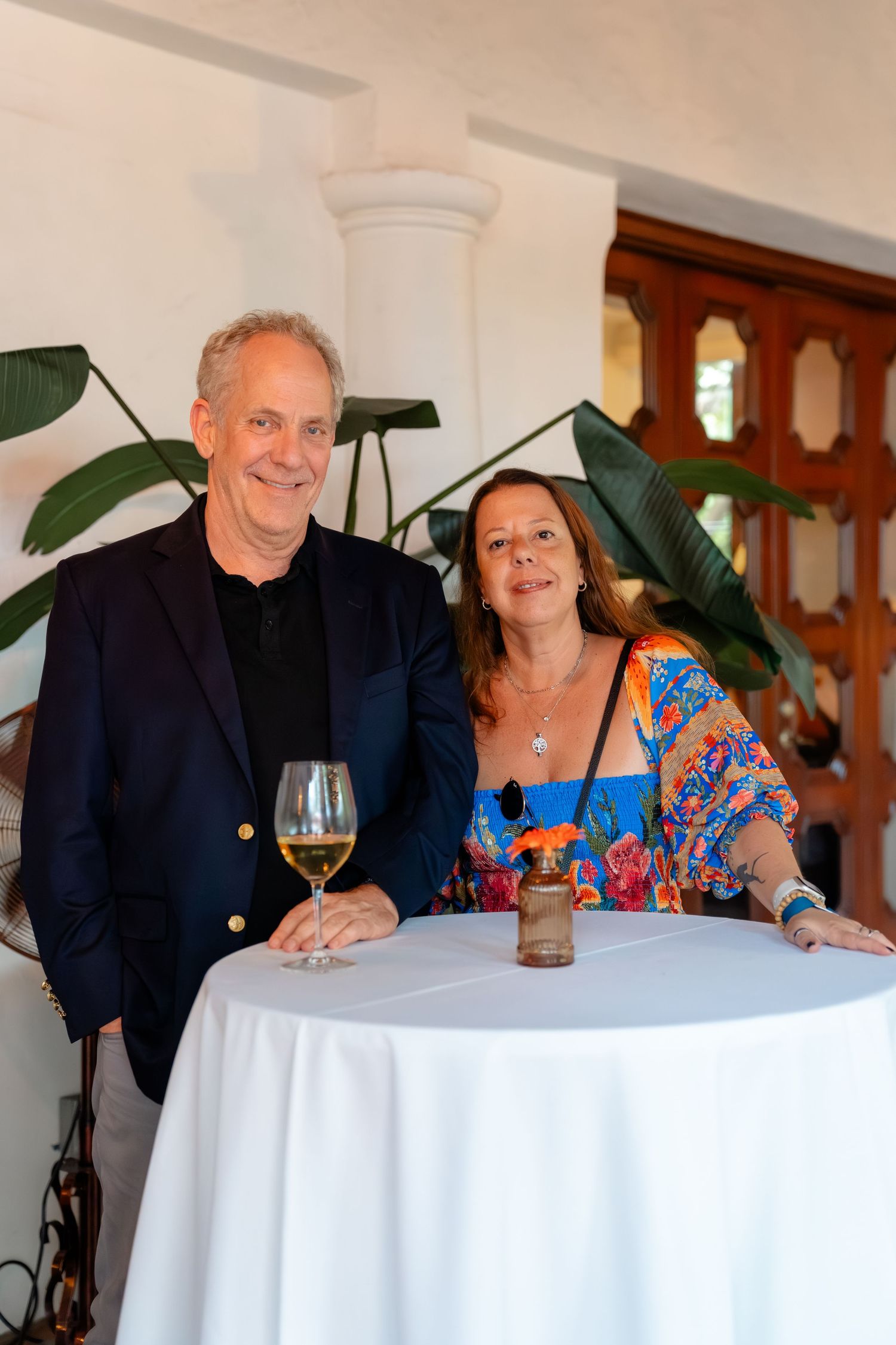Couple smiling at a high-top table with white wine and a drink at an elegant indoor venue.