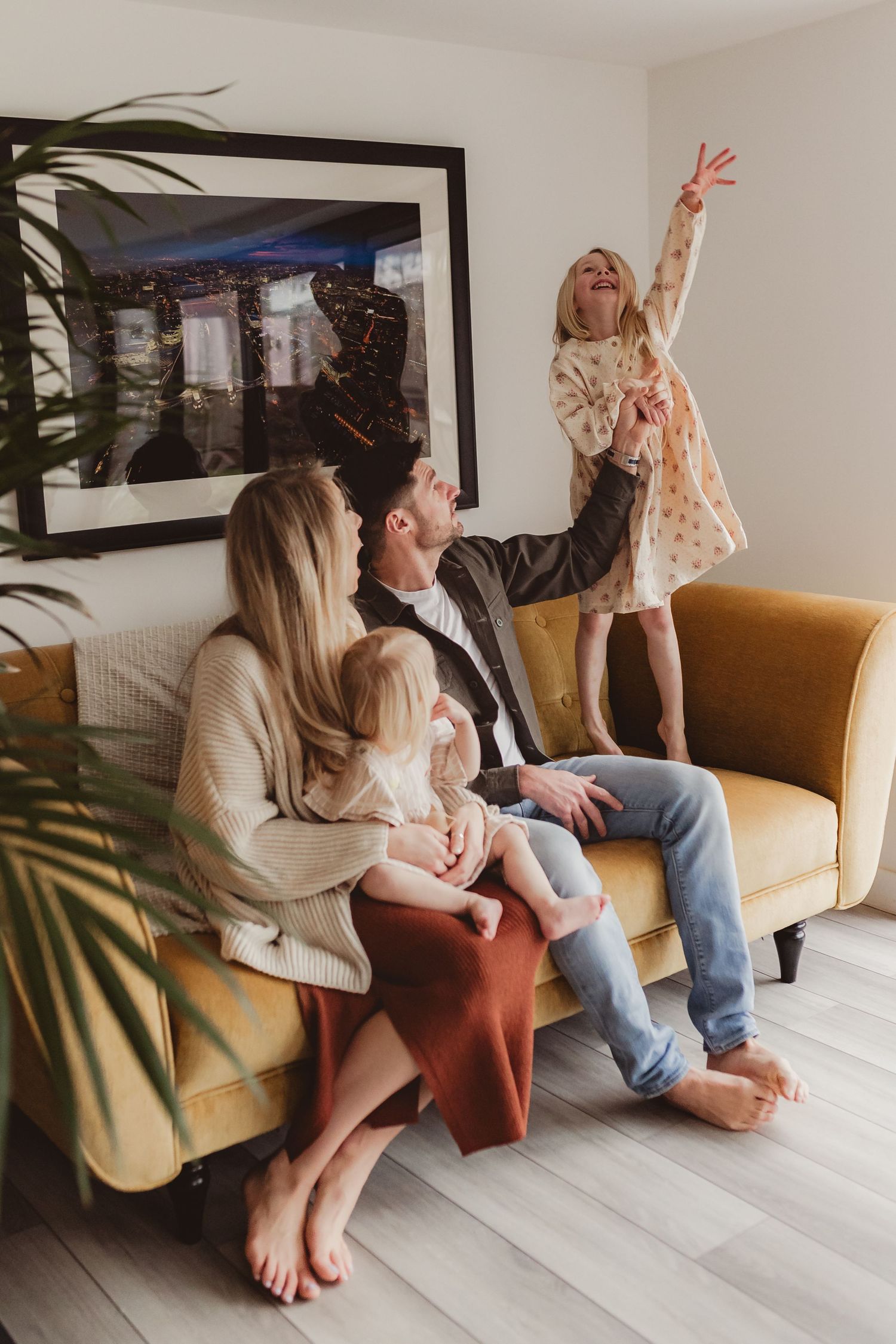 Joyful parents laughing and holding their smiling baby during a warm and candid family portrait session indoors.