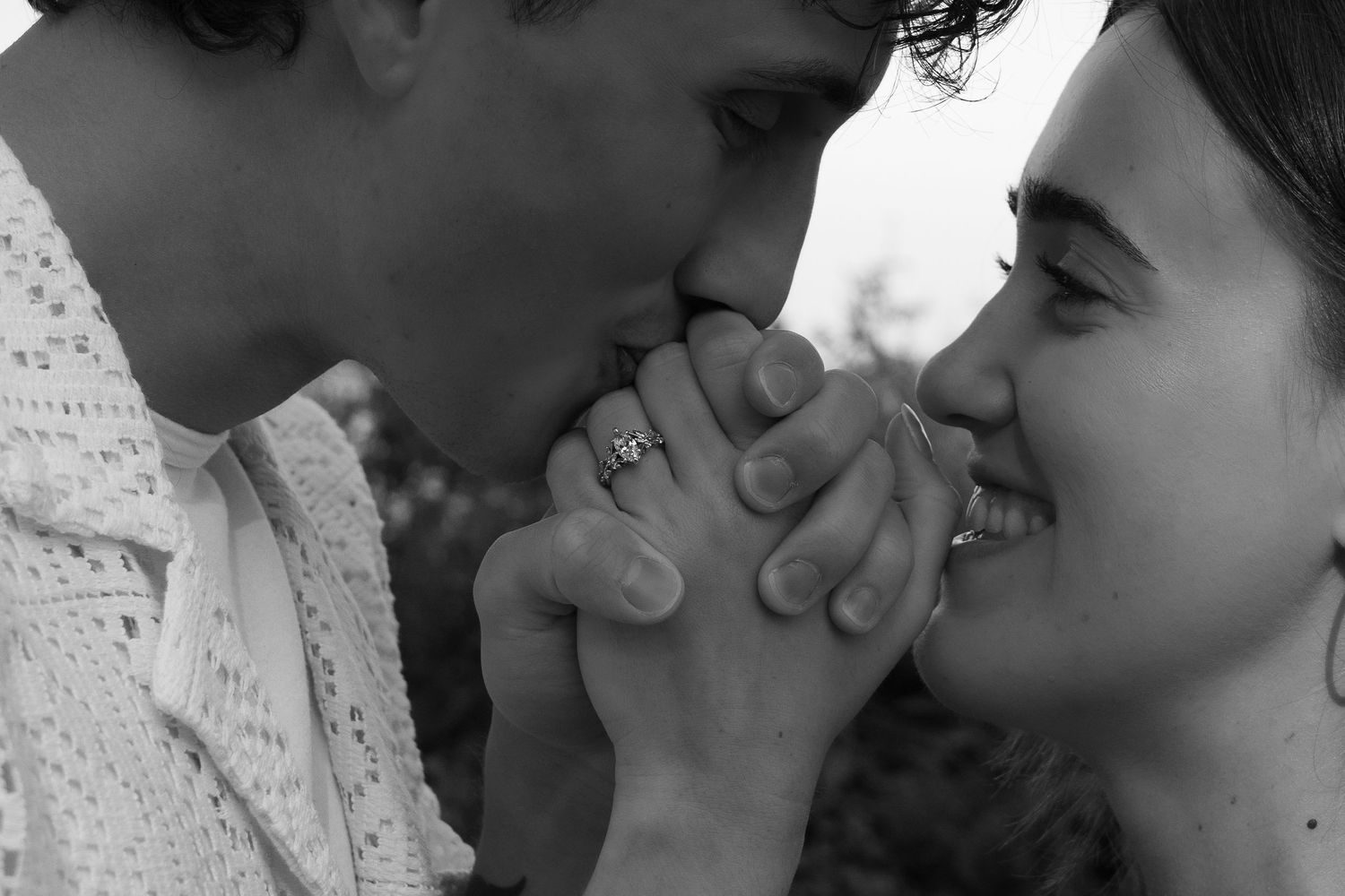 Black and white romantic close-up of two people holding hands together and smiling at each other. captured by Savvy Photography - Seattle