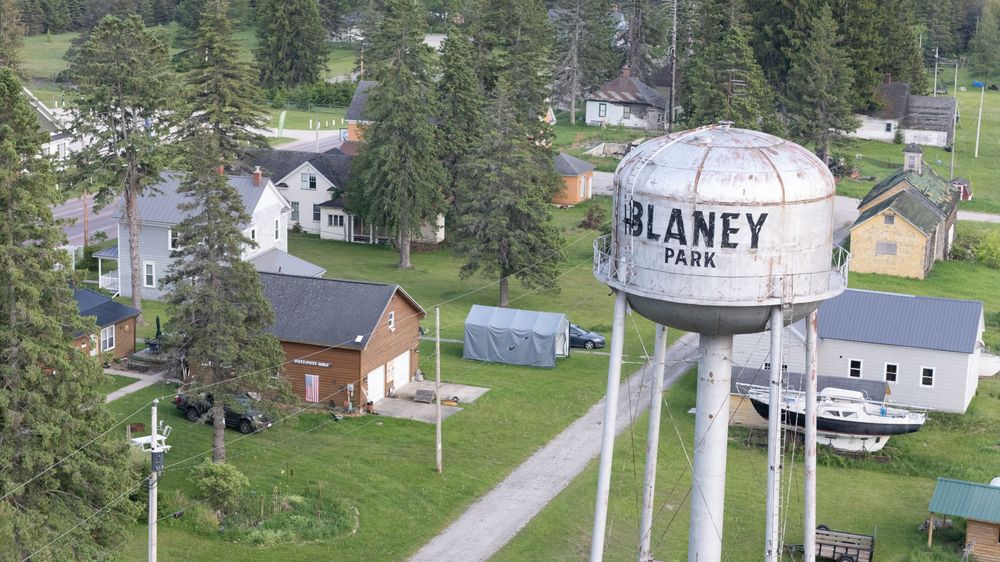 Aerial view of Blaney Park water tower surrounded by small town homes and green trees in Michigan.
