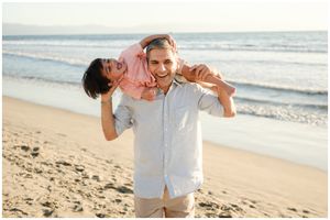 Sayulita family photographer, playful beach carry at sunny shoreline, candid couple moment in natural light.