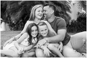 Punta Mita family photography session, black and white family portrait near palm trees, candid outdoor lifestyle moment.
