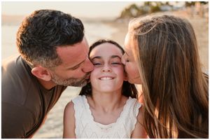 Riviera Nayarit family photographer, parents kissing daughter at golden hour beach, candid family moment natural light.