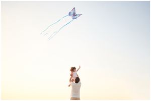 Family beach photoshoot in Punta Mita, Punta Mita family photography session, father lifting child flying kite at sunset.
