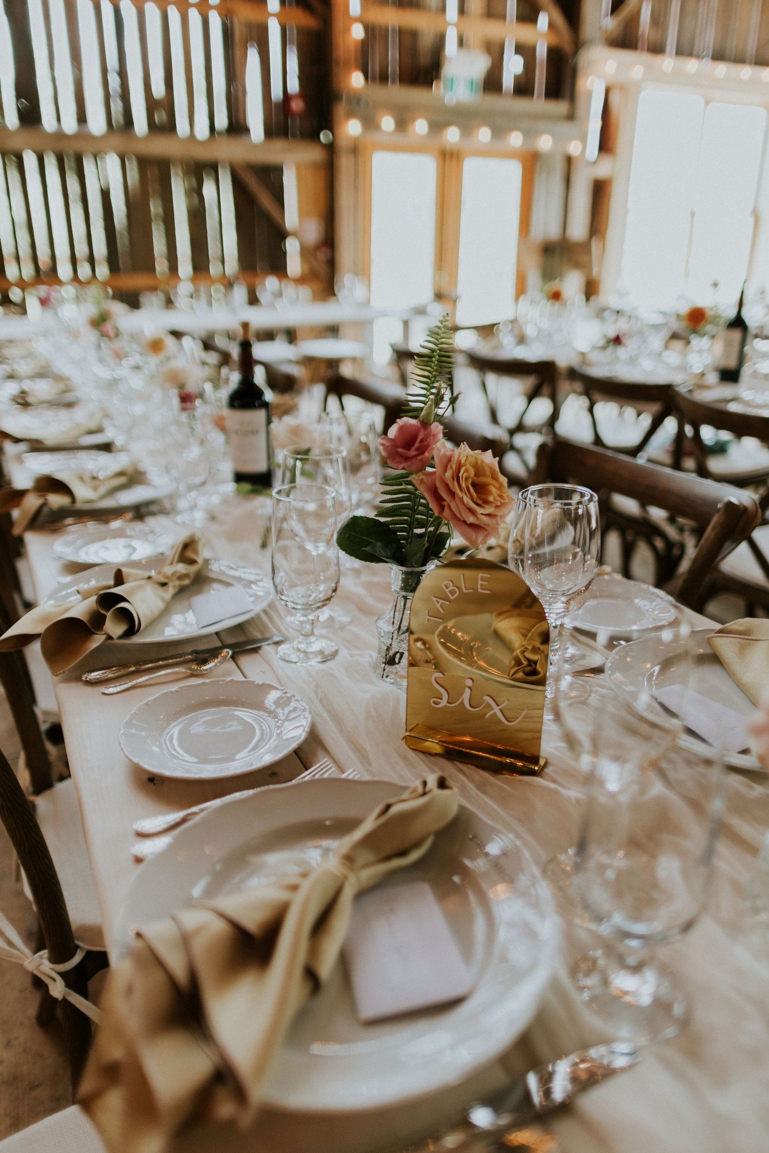 Rustic elegant barn wedding reception setup with long tables aligned for natural guest flow and conversation.