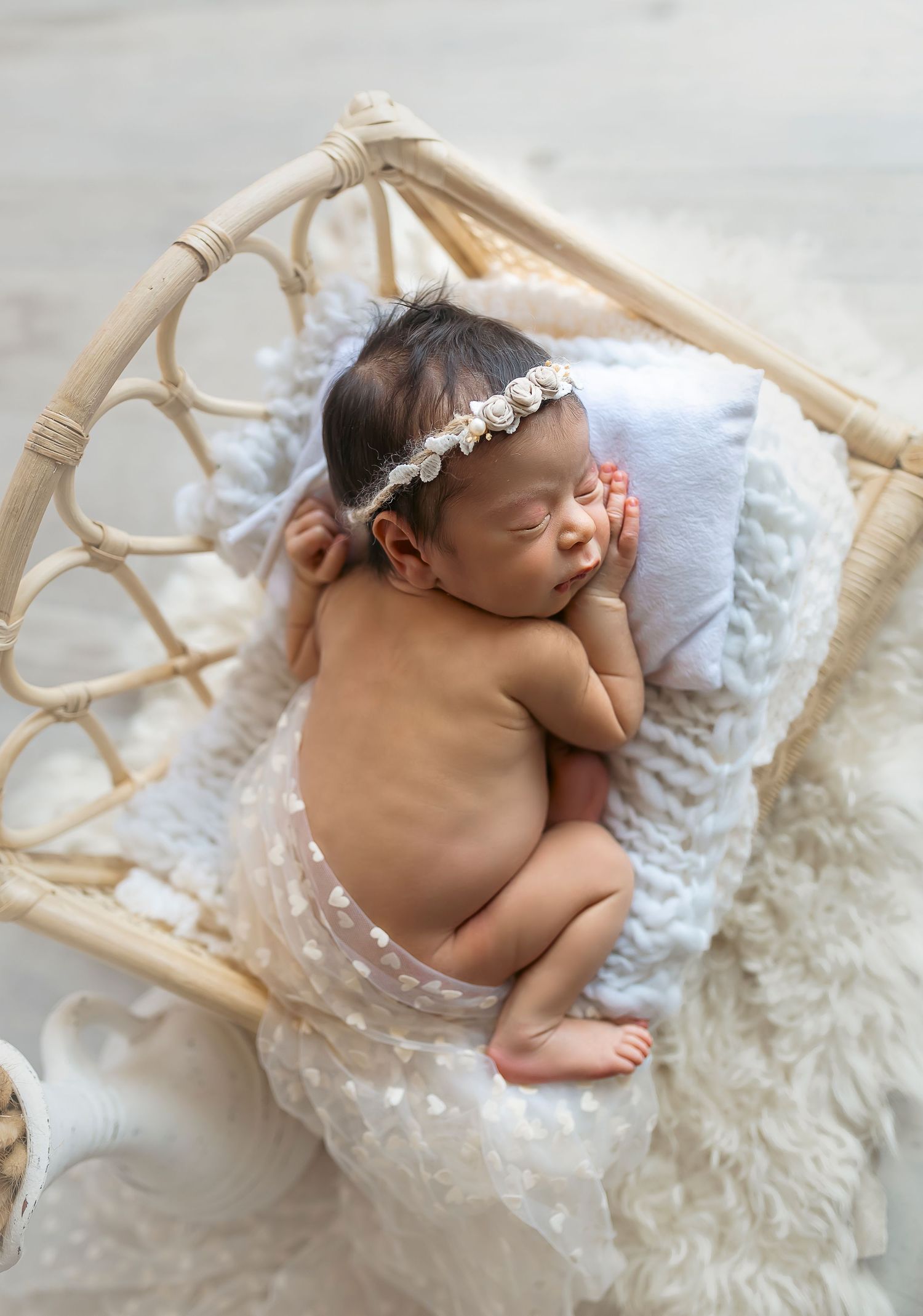 bebe recien nacida acostadita durmiendo en una cama de rattan decorada de blanco imagen tomada desde arriba hacia abajo