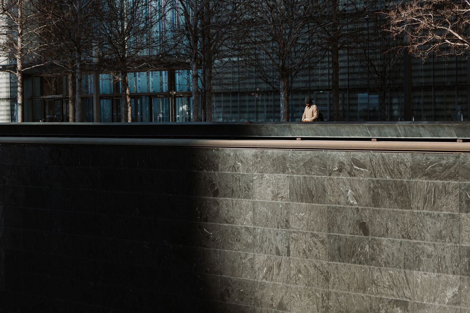 Stone wall with engraved text casting shadows in dramatic lighting.