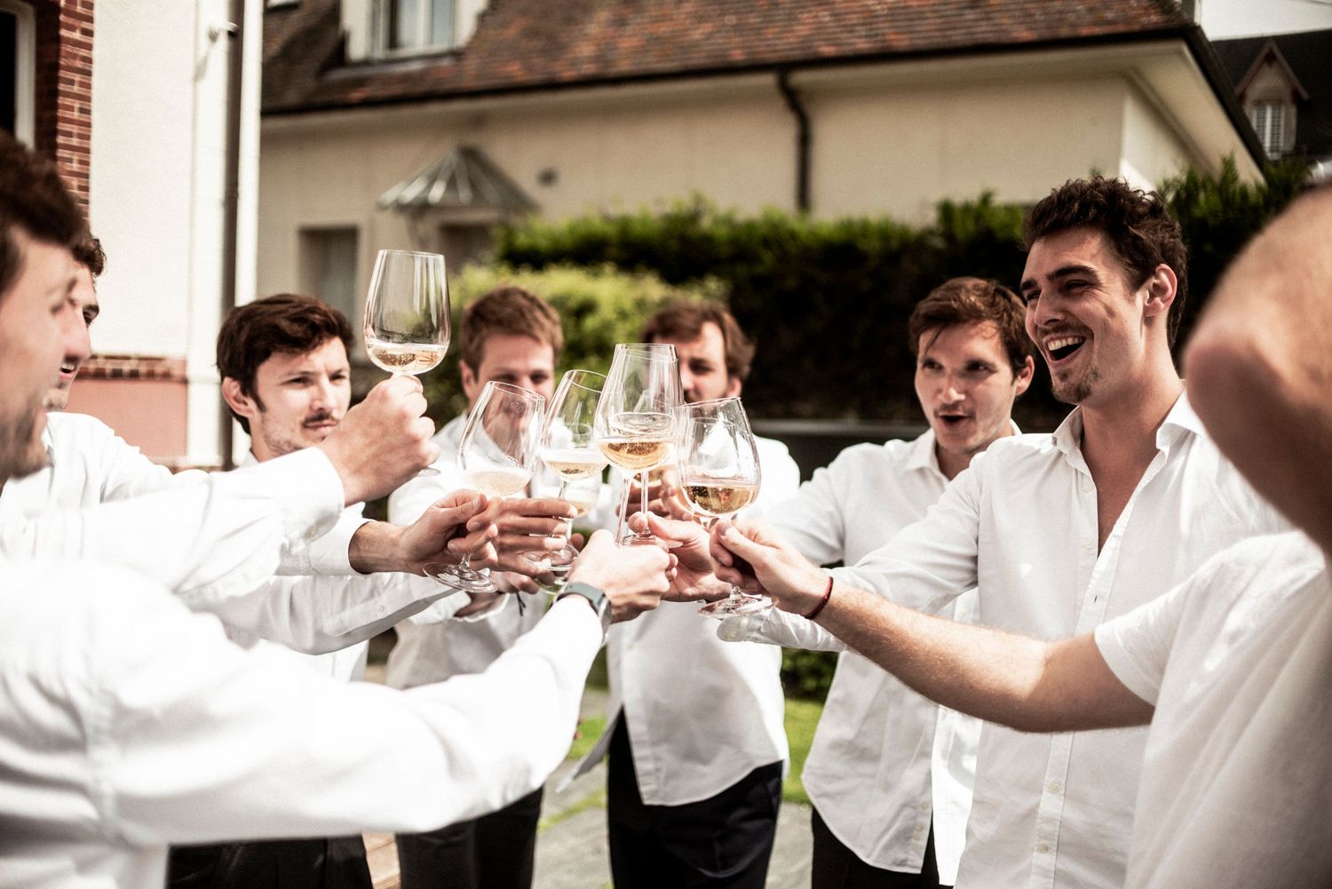 A group in white shirts toasts with wine glasses during a celebratory gathering.