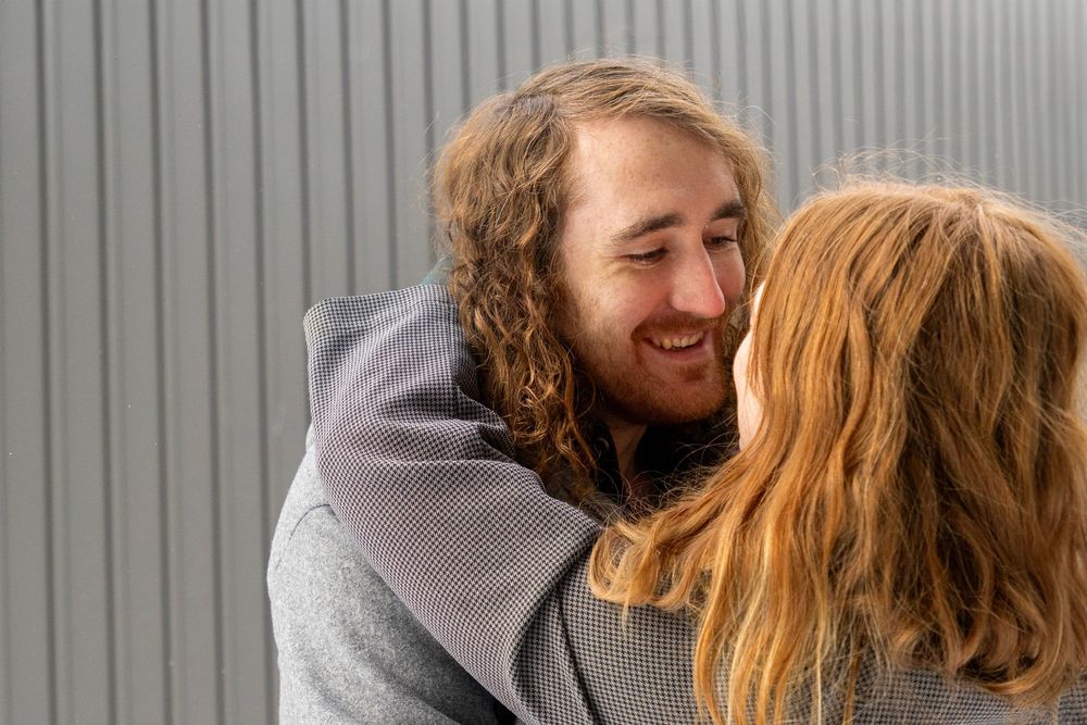 a couple admiring one another in the winter with the girls hands wrapped around his neck, leaned in. Shot taken over the girls shoulder