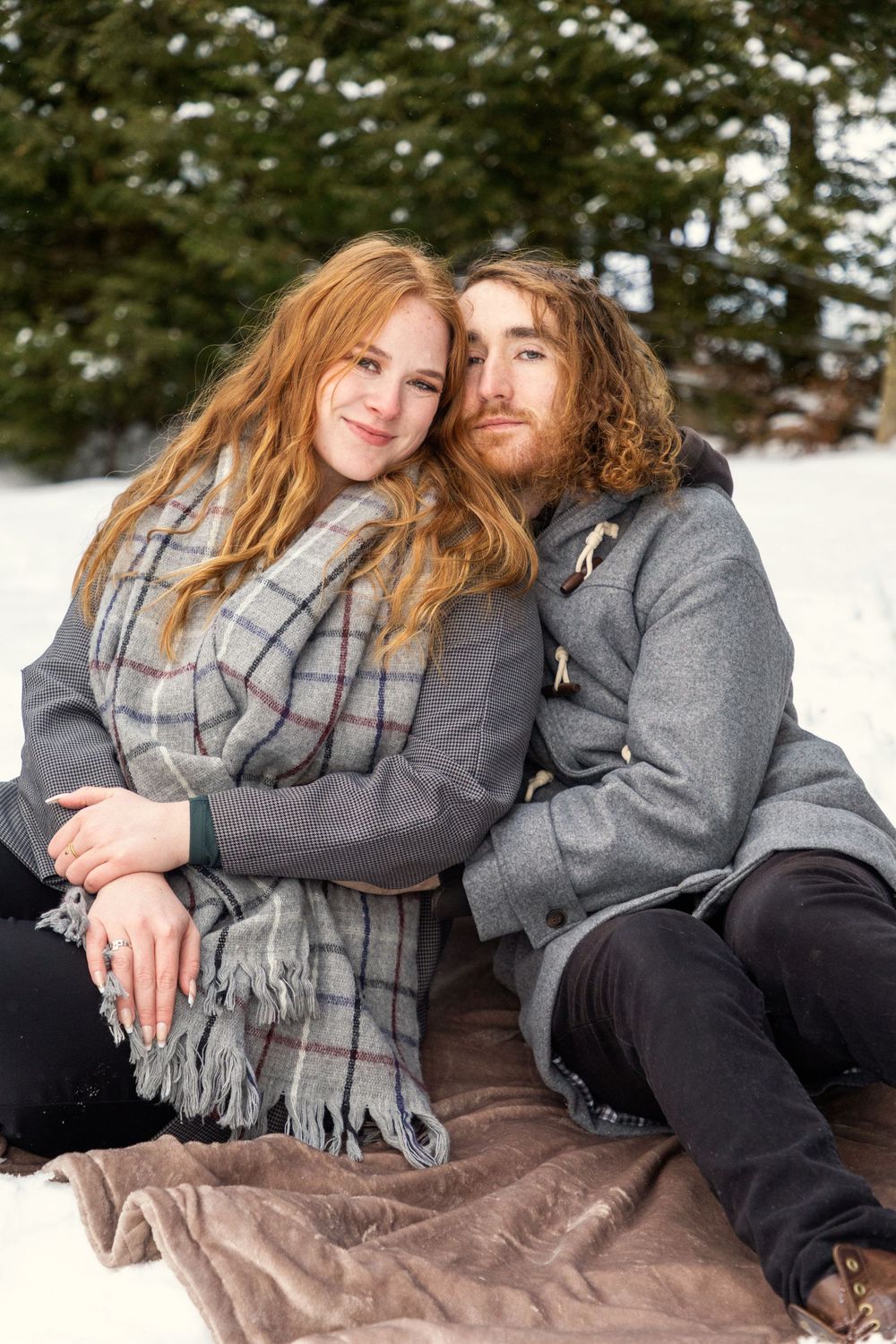 A couple cuddling in the snow on a blanket