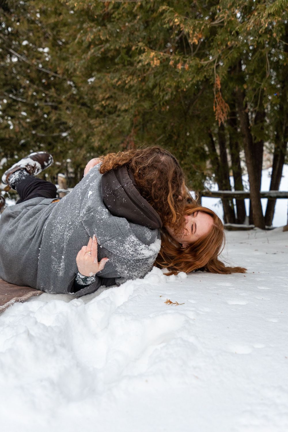 A couple rolling over each other in the snow