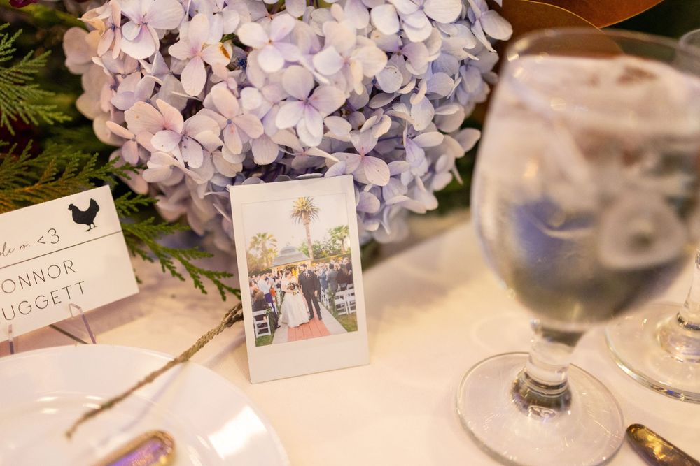 Elegant table settings with delicate purple hydrangea floral centerpieces and place cards at a wedding reception.