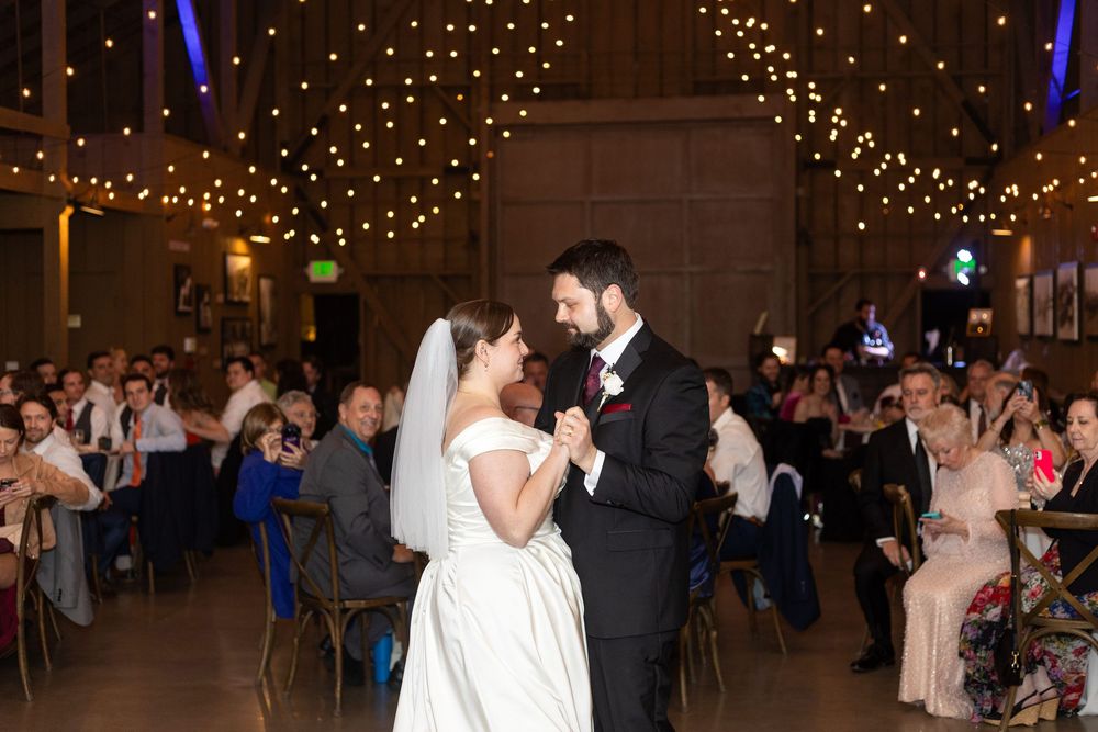 Romantic first dance moment at an elegant wedding reception under twinkling lights.
