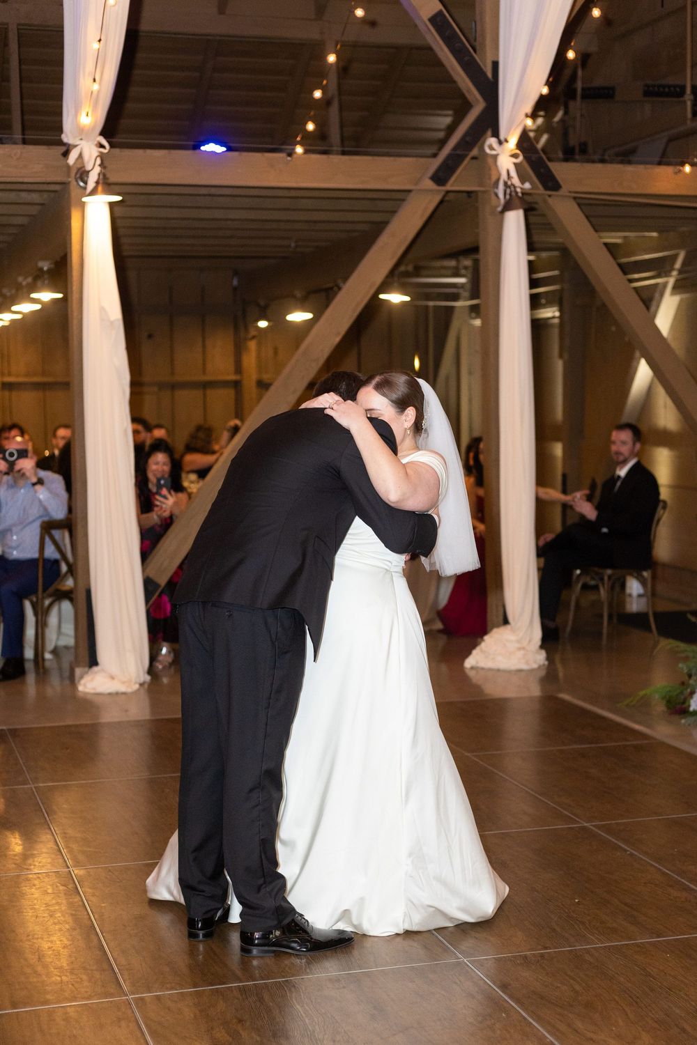 Couples dancing during a romantic first dance at a rustic barn wedding reception.